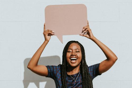 Cheerful black woman showing a blank speech bubble - 1208377