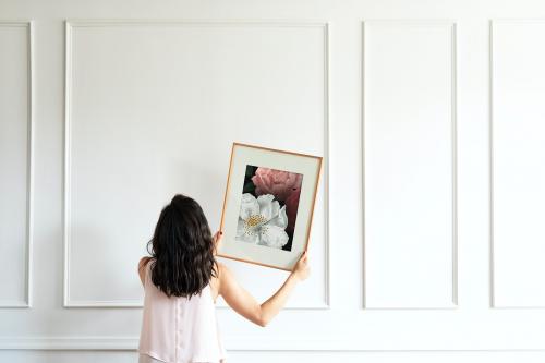 Curator hanging floral art frame mockup on the wall - 1209131