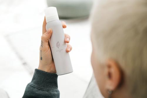 Blond hair woman holding a white spray bottle mockup - 1215191