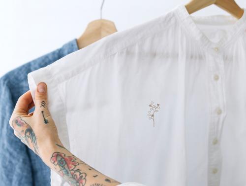 Woman holding a white shirt mockup on a rack - 1215288