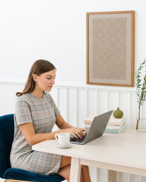 Woman sitting on a chair by a frame mockup on the white wall - 1215318