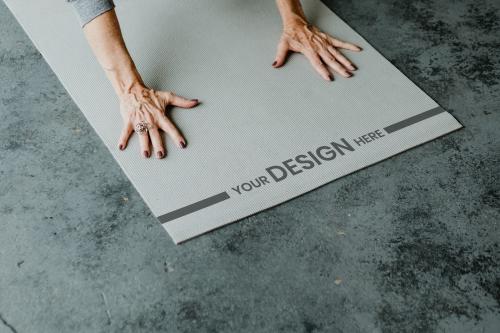 Woman practicing a Adho mukha svanasana pose on a gray mat mockup - 1201574