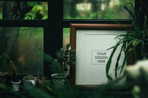 Blank photo frame with houseplants by the window - 844055