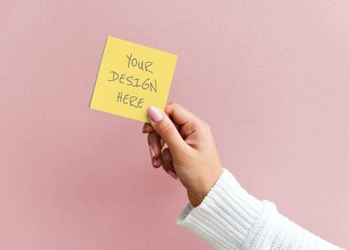 Woman holding a sticky note mockup against a pink wall - 894803