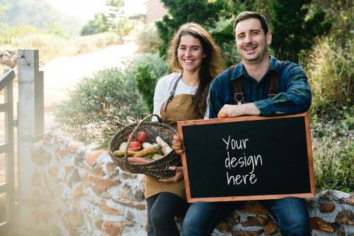 Farmer couple holding a vegetable basket and a blackboard mockup - 598453