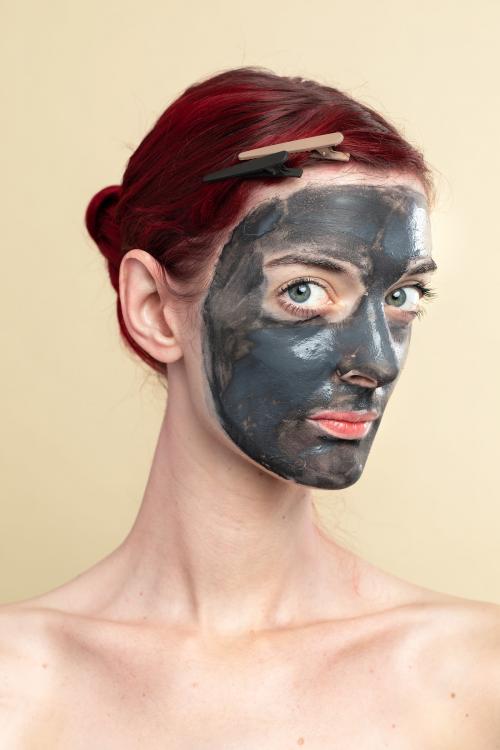 Beautiful woman wearing an activated black charcoal mask for facial treatment - 2054049