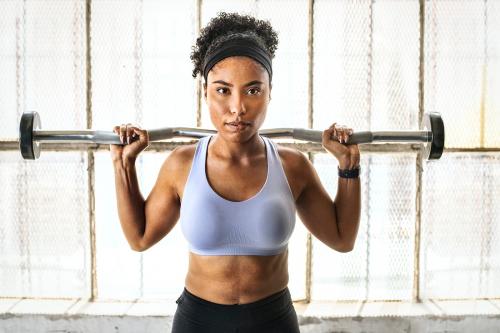 Woman exercising weighlifting with barbell at fitness gym - 2109028