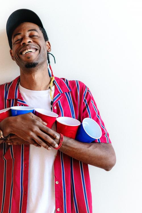 Cheerful young man holding red and blue cups - 2114581