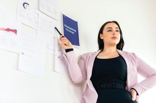 Businesswoman presenting a marketing strategy on a white wall - 2204671