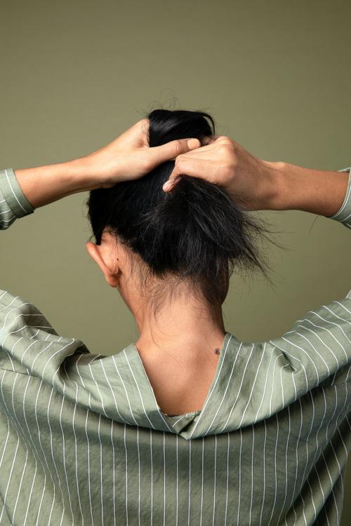 Rear view of a woman putting her long hair up - 2210592