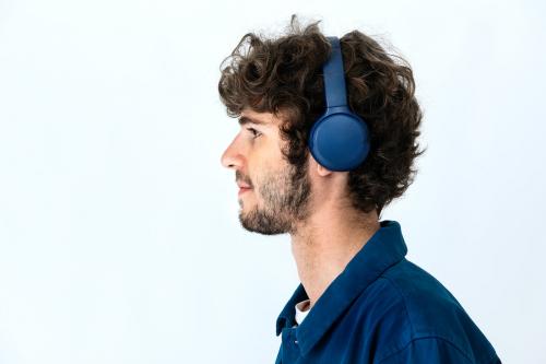 Cheerful man listening to music through headphones in a white background - 2223211