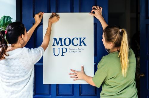 Women putting up a poster mockup - 580833