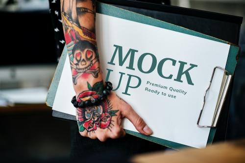 Tattooed woman holding a paper mockup on a clipboard - 580857