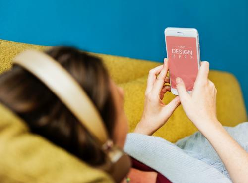 Woman using a phone mockup on a sofa - 580890