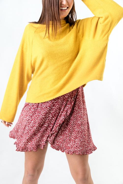 Cheerful woman wearing a mustard yellow sweater on a red flower dress - 2288558