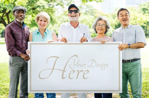 Group of diverse seniors showing a poster mockup in a garden - 580903