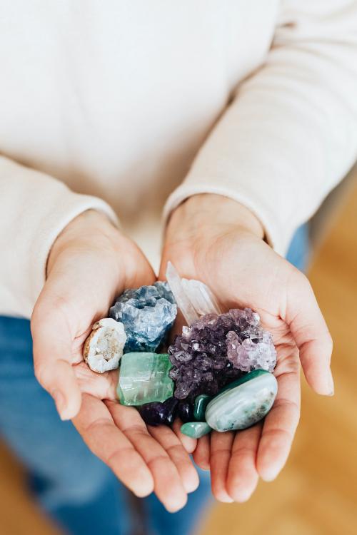 Woman with a hand full of healing crystals - 2285579