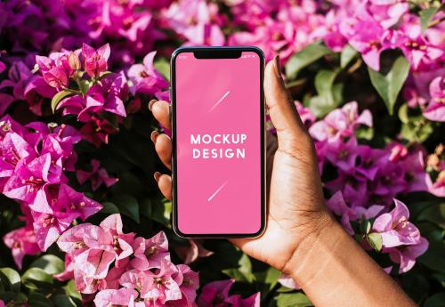 Woman holding a mockup phone over a pink bougainvillea - 560808