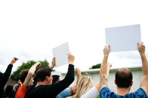 Rear view of activists showing papers while protesting - 525635