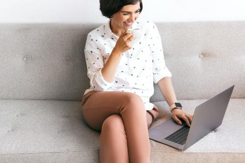 Happy woman sipping coffee while working - 2030303