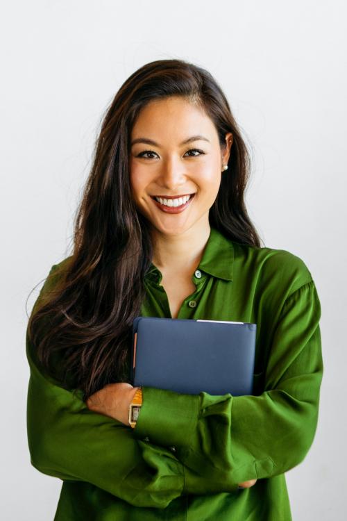 Cheerful woman in green shirt holding blue notebook - 2030438