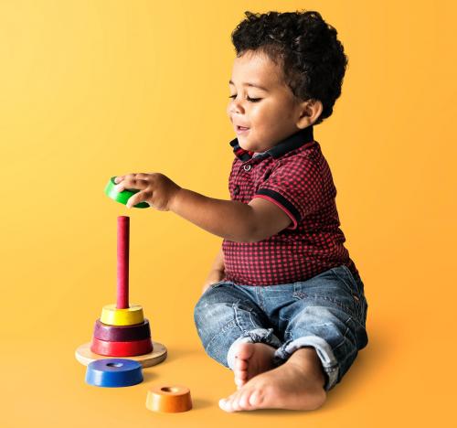 Happy boy enjoying stacking colorful discs - 536049