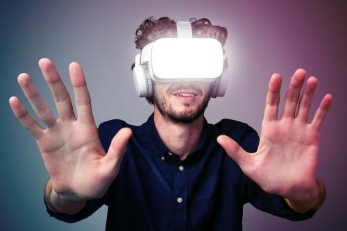 Young man using a VR headset in a two tone background - 2225303