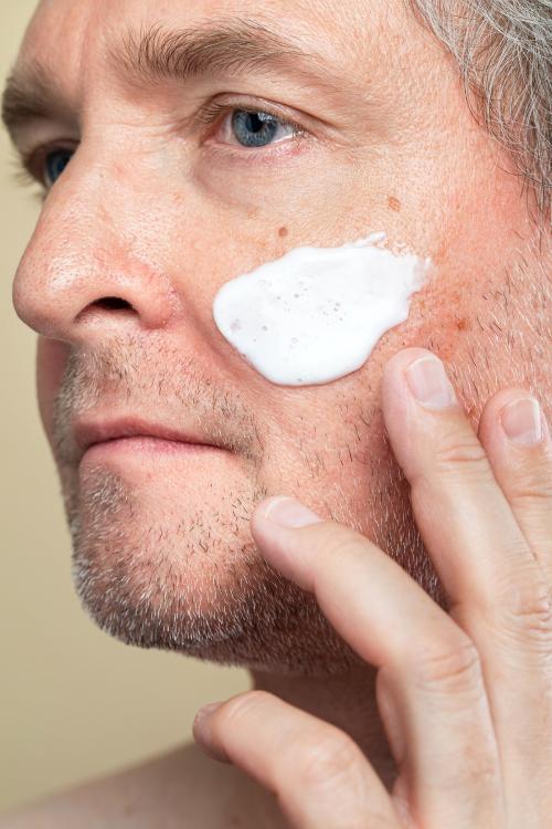 Closeup of a senior man using a moisturizing cream for skincare routine - 2053996