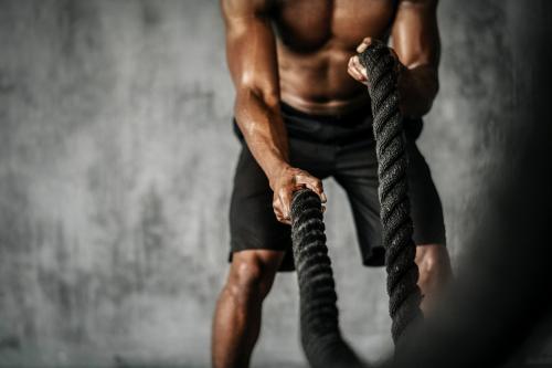 Muscular man working out on the battle ropes in a gym - 2107452