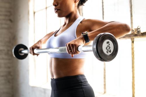 Woman exercising weighlifting with barbell at fitness gym - 2107433