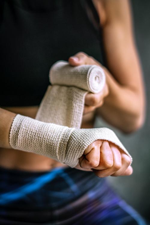 Female boxer putting a strap on her hand - 2108986