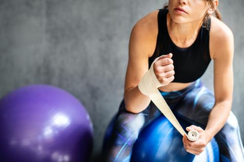 Female boxer putting a strap on her hand - 2107298