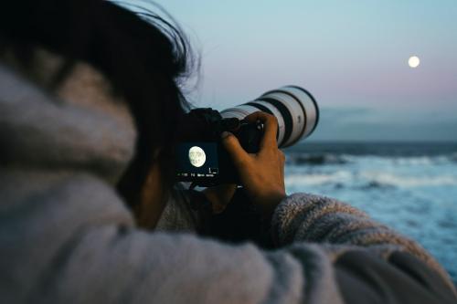 Photographer capturing the Moon by the sea - 2221685