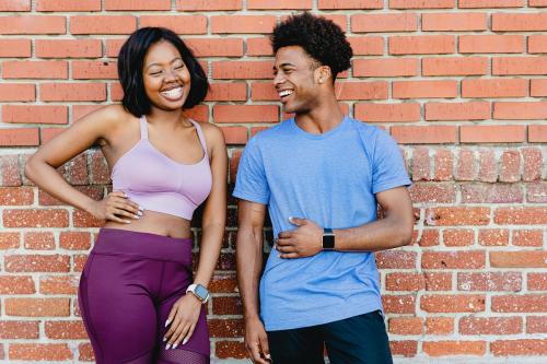 Sporty couple standing by a brick wall - 2046414