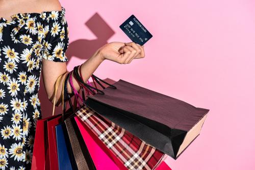 Woman carrying shopping bags against a pink background - 2054428