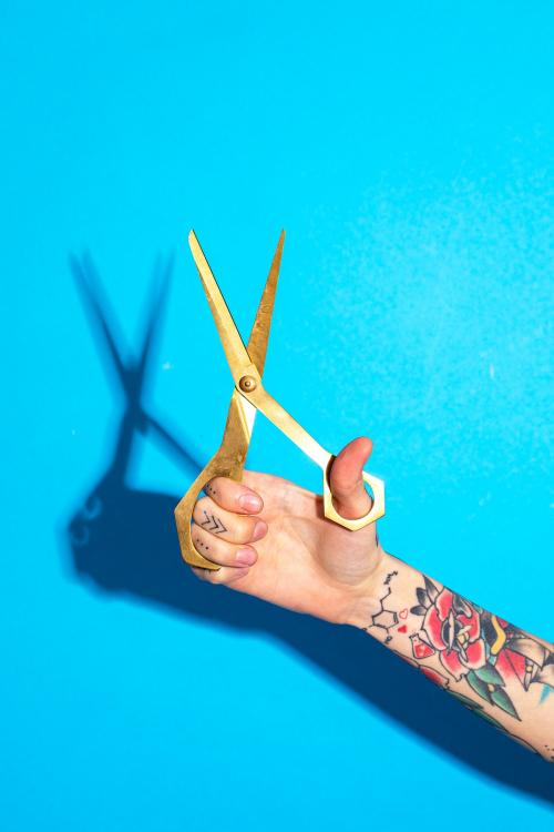 Tattooed hand holding a pair of scissors - 2055962