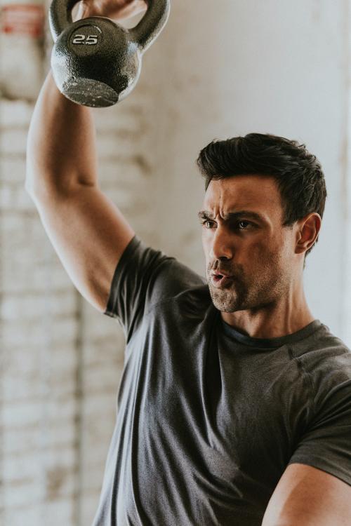 Sportive man lifting a kettlebell - 2107377