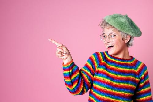 Portrait of a cute cheerful girl wearing glasses pointing side ways in a pink background - 2209621