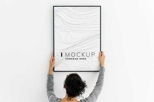 Woman putting up an art piece mockup at home - 502830