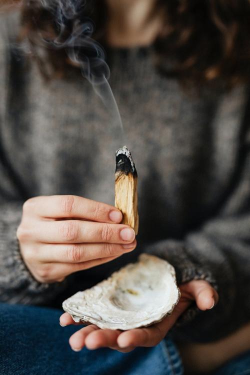 Woman buring palo santo for cleansing her home - 2281786