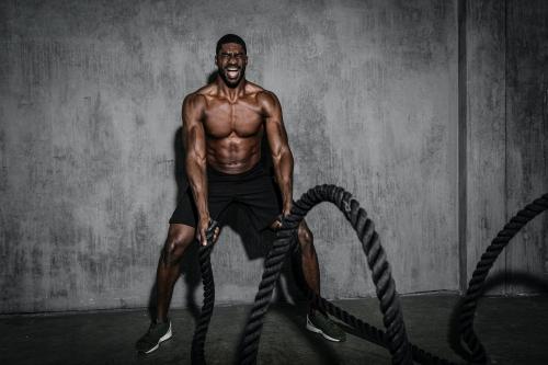 Muscular man working out on the battle ropes in a gym - 2109017