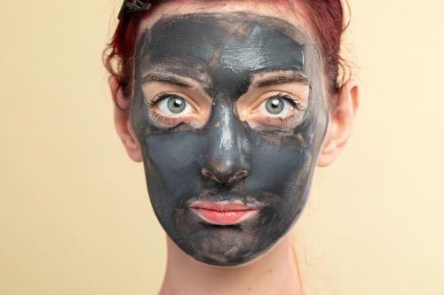 Beautiful woman wearing an activated black charcoal mask for facial treatment - 2053991