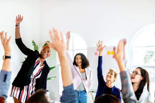 Happy women raising their arms in a meeting - 2204207