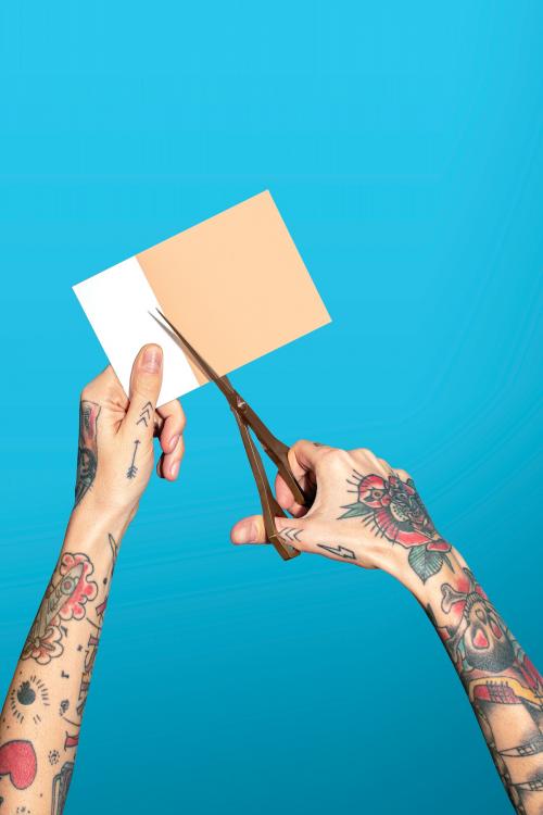 Hands with tattooed holding scissors cutting paper - 2054343