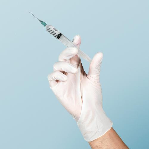 Hand wearing a white glove holding a syringe - 2093819
