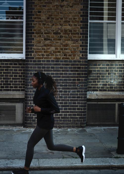 Woman listening to music while jogging in a city - 2025088