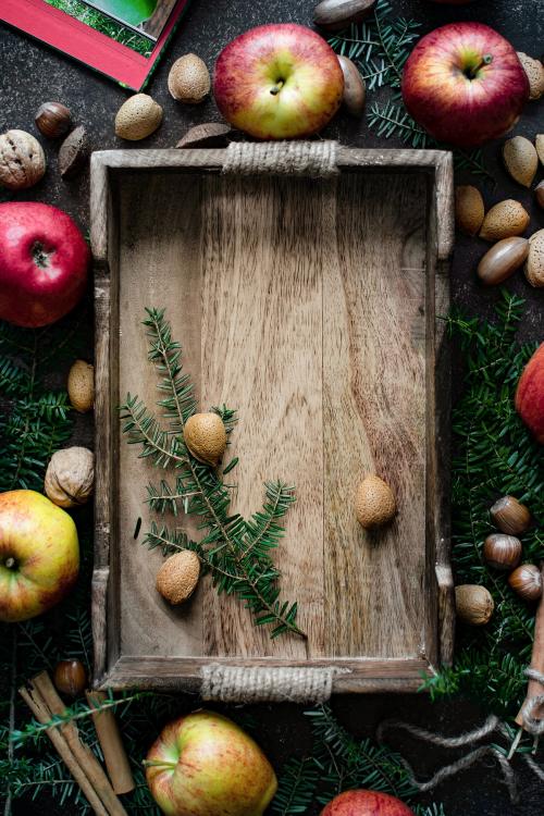 Apples with mixed nuts around a wooden tray - 2049769