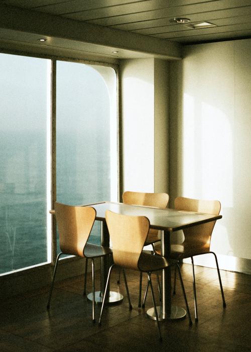 Empty table and chairs by a window on a ferry at sea - 2273385