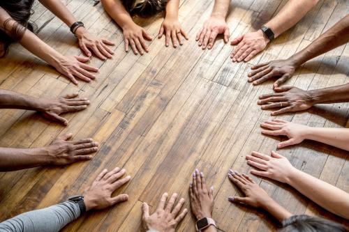 Diverse hands forming a circle on the floor - 2041690