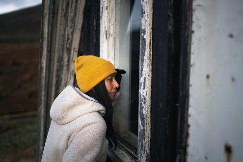 Woman looking through an A-Frame cabin window - 2042799